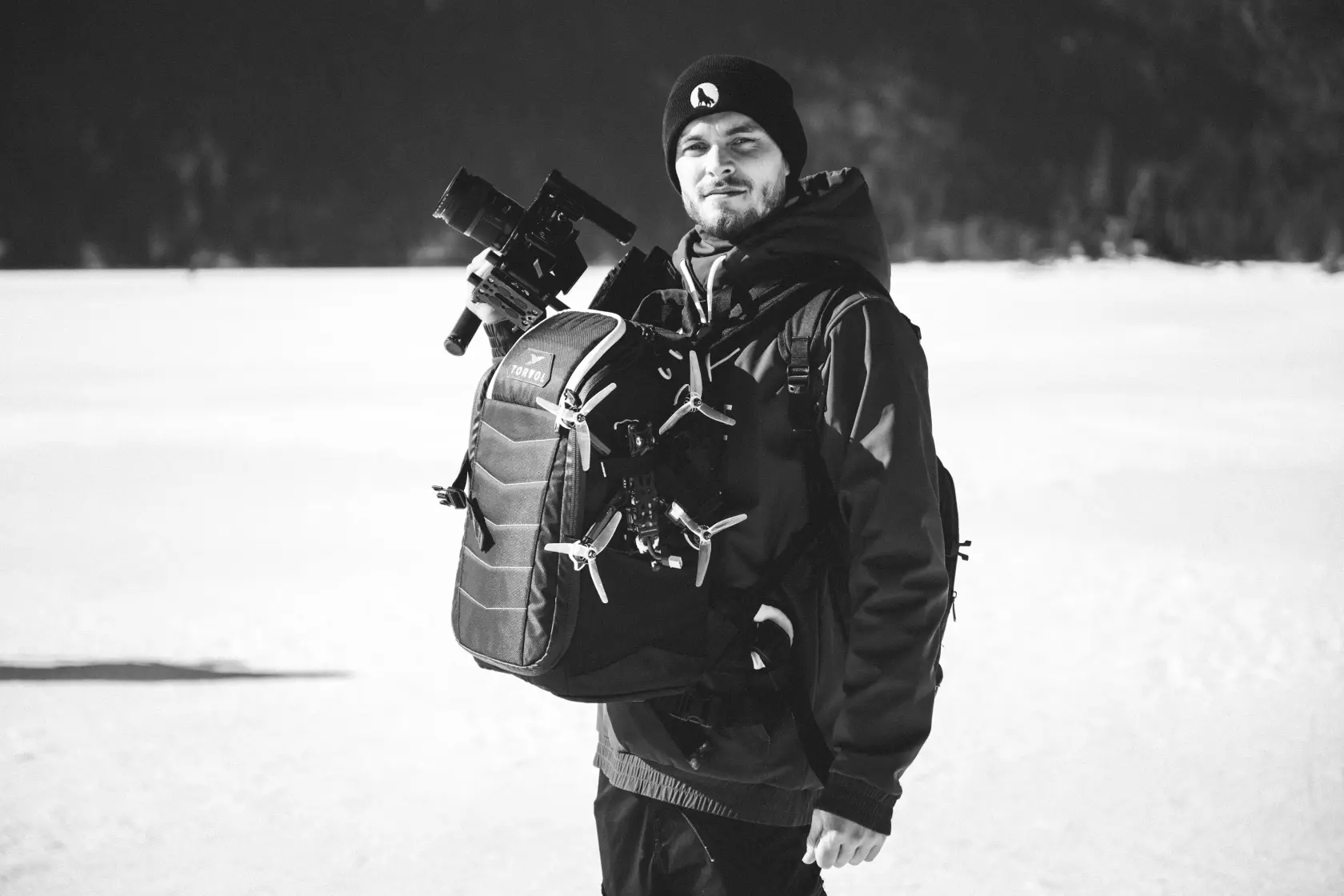 Drohnenpilot und Kameramann Max mit Videoequipment in Schneelandschaft
