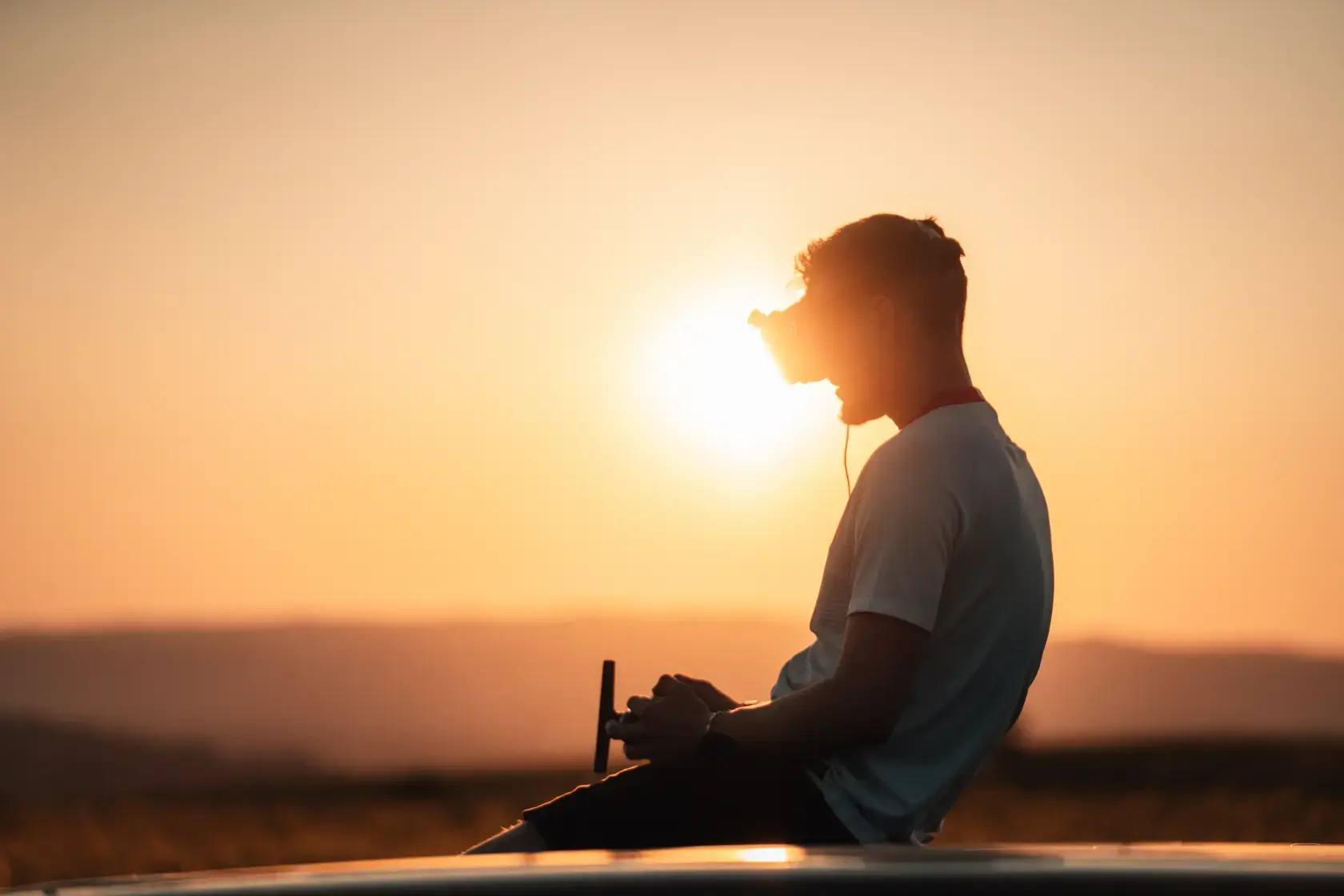 Drohnenpilot mit VR-Brille und Controller bei Sonnenuntergang